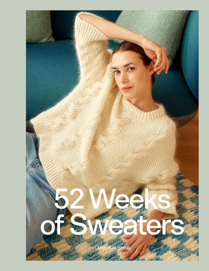 A woman wearing a chunky cream cable-knit sweater sits on a patterned rug in front of a blue sofa. Large white text across the lower half reads '52 Weeks of Sweaters' with small 'LANE FASHIONING' underneath.